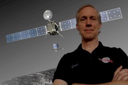 Joel Parker standing in front of an image of the Rosetta spacecraft with the jet coming off it. Photo credit: Joel Parker