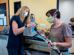 Graduate student Teyha Stockman, right, shows off her homemade bell cover made from medical mask material that helps decrease aerosol spread on her clarinet to mechanical engineering professor Shelly Miller in MillerÕs mechanical engineering laboratory on the CU Boulder campus. The two researchers have been studying how aerosols spread with vocal and instrument performance. (Photo by Glenn Asakawa/University of Colorado)